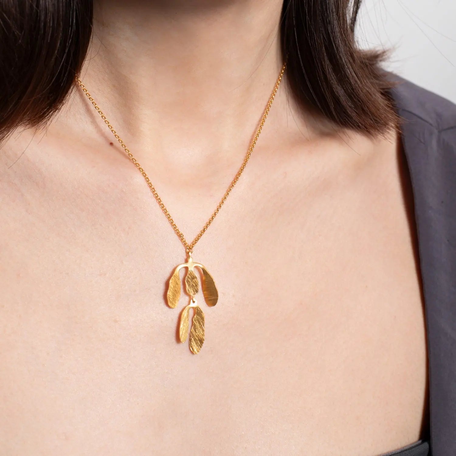 Gold necklace with leaf pendants worn by a person